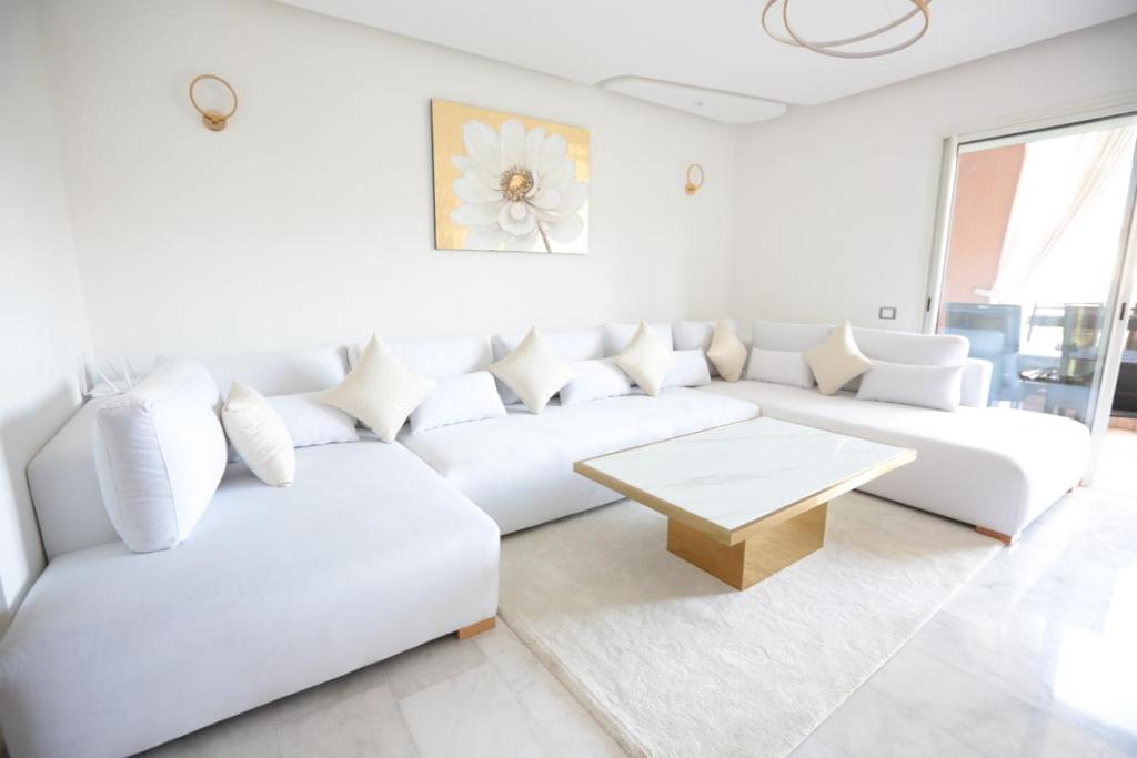 a white living room with a white couch and a table at APPARTEMENT RIAD WHITE GOLDEN in Marrakesh