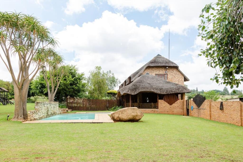 een huis met een rieten dak en een zwembad bij Pride Aloe in Muldersdrift