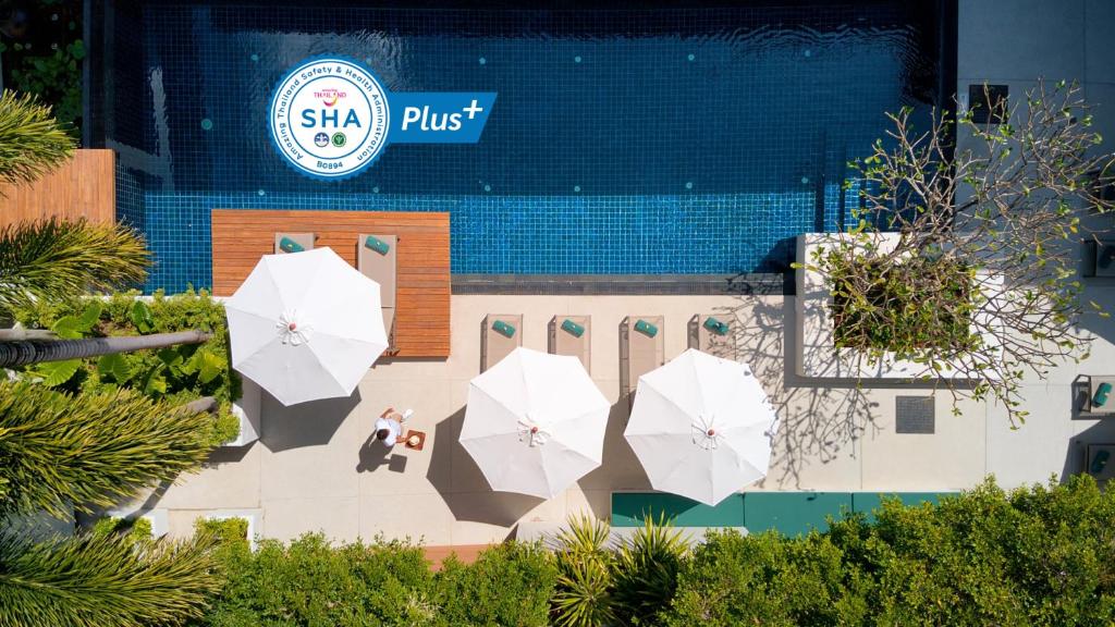 Outrigger Surin Beach Resort - SHA Extra Plus في شاطئ سورين: مجموعة من المظلات البيضاء أمام المبنى