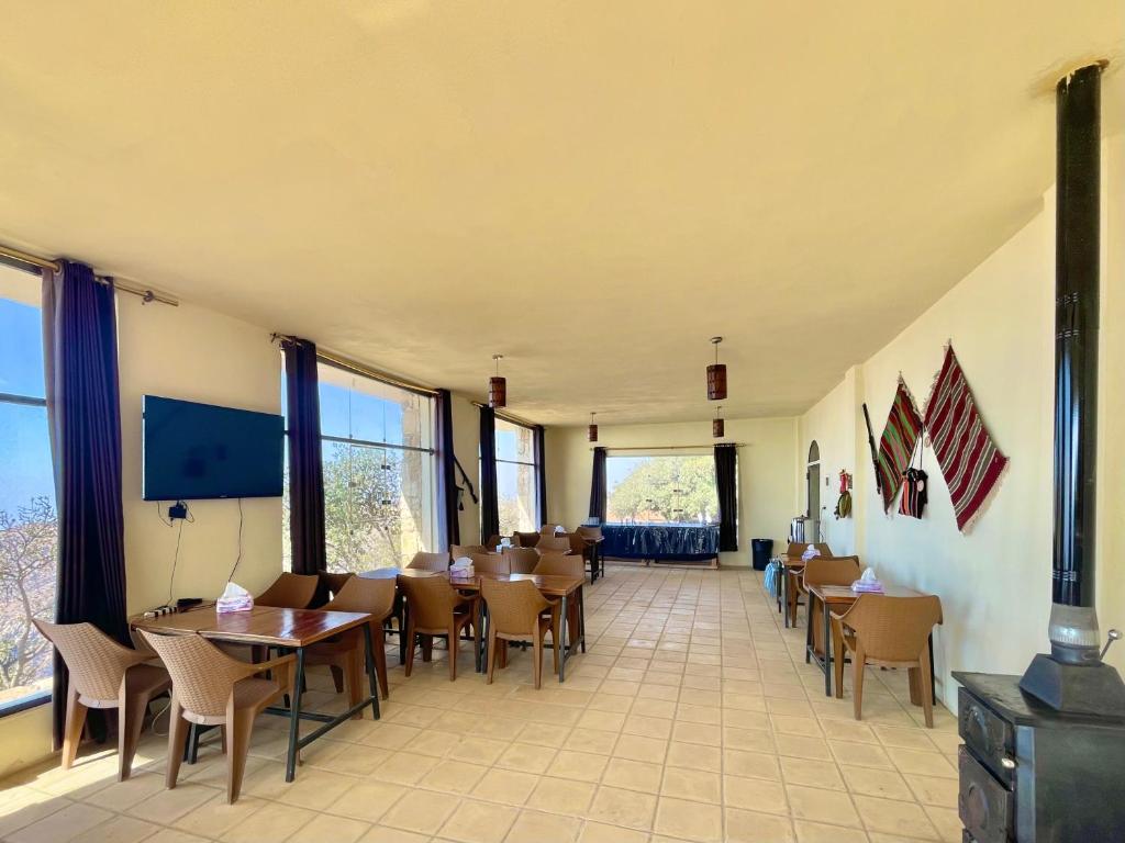 ein Esszimmer mit Tischen, Stühlen und Fenstern in der Unterkunft Jabal Dana Hotel - the highest hotel in Jordan in Dana