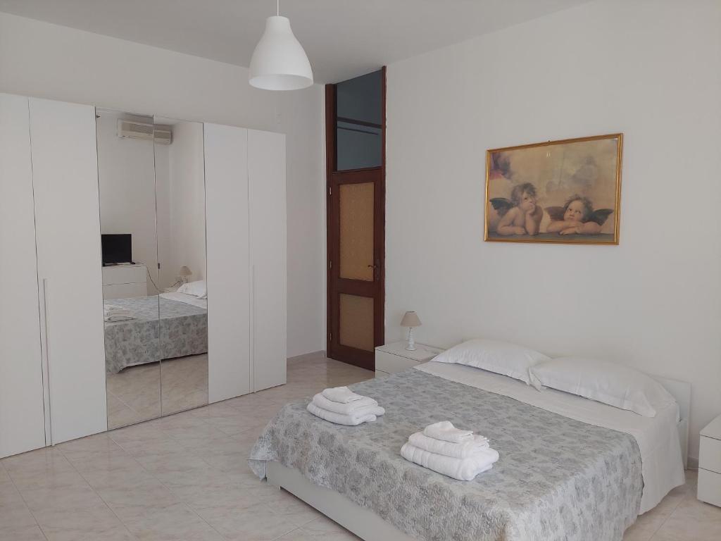 Un dormitorio blanco con una cama con toallas. en Domus Dejanas - Appartamento 180 mq a Quartu, en Quartu SantʼElena