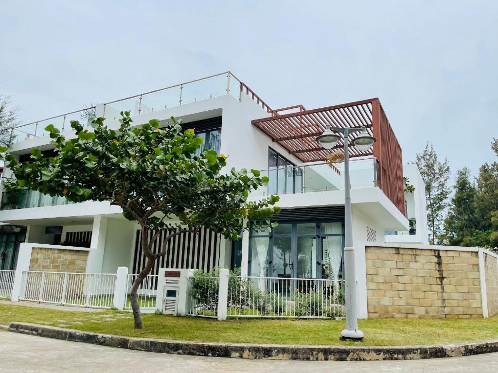 a white house with a tree in front of it at Villa By Z-Mimosa 617 in Vung Tau