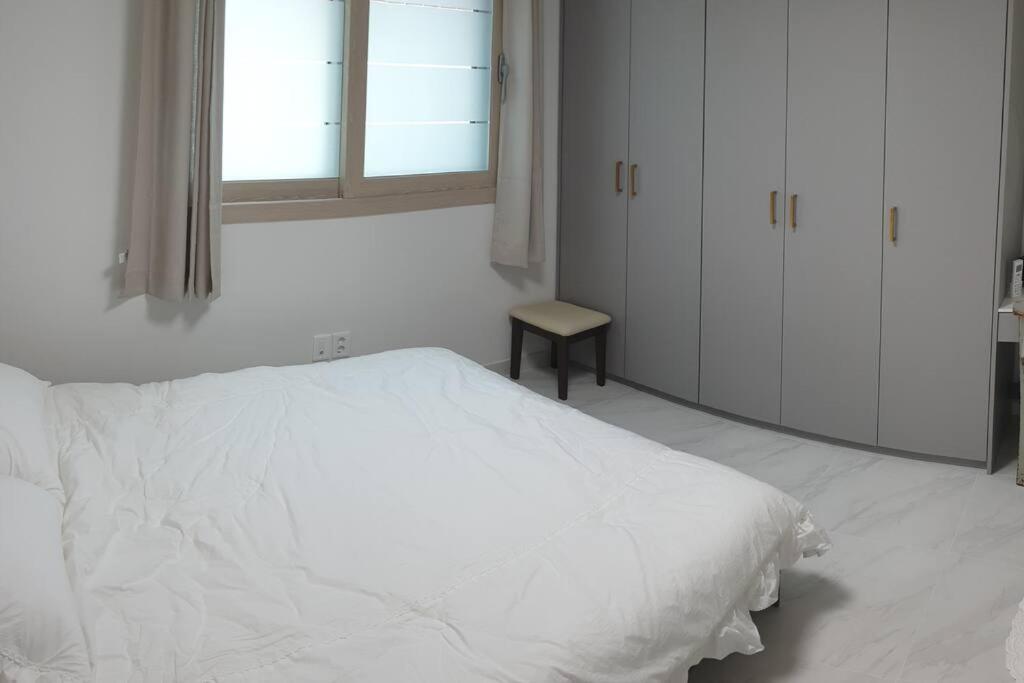 a white bedroom with a white bed and a window at Gyeongju Sugi's Guesthouse in Gyeongju