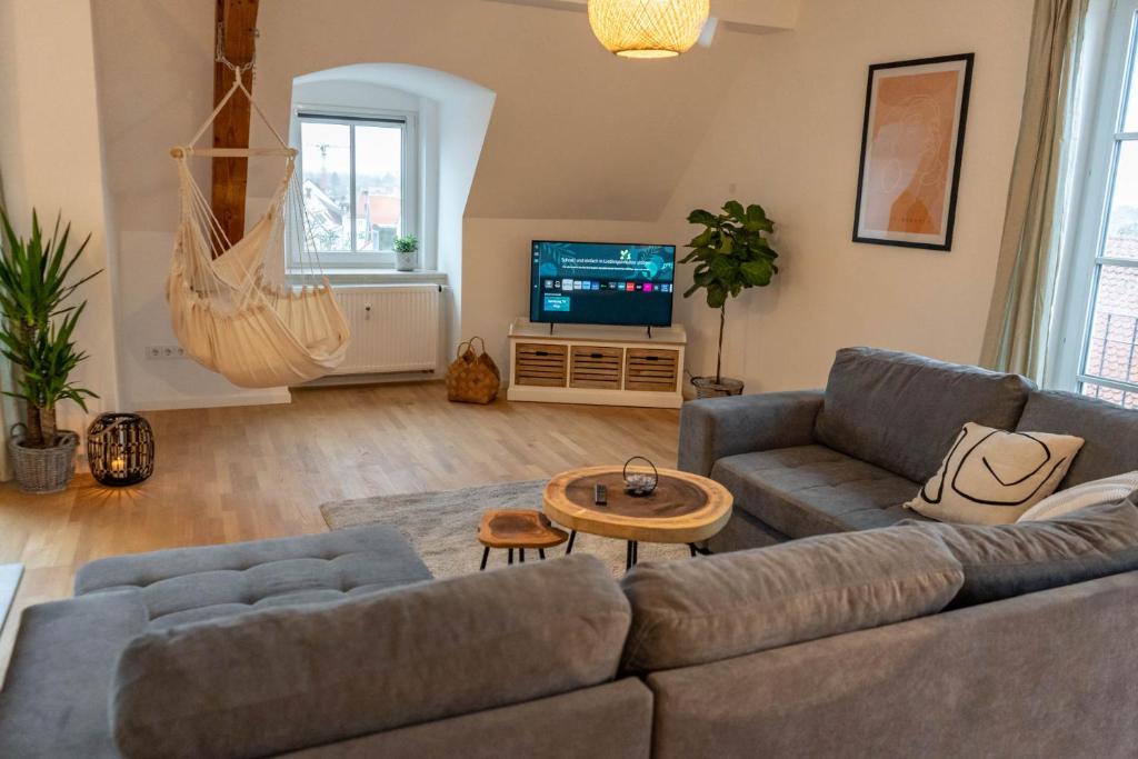 a living room with a couch and a tv at Hejm Apart - Design Maisonette-Ferienwohnung "Zugspitze" in Mering