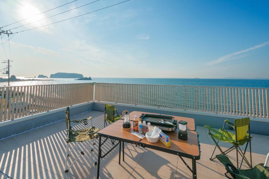 Ryū shi ma Ocean View Villa في Kyonan: شرفة مع طاولة وكراسي والمحيط