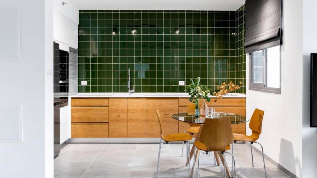 a kitchen with a table and a green tiled wall at סוויטה מדהימה במרכז הארץ-amazing suite in the center of the country in Beʼer Ya‘aqov