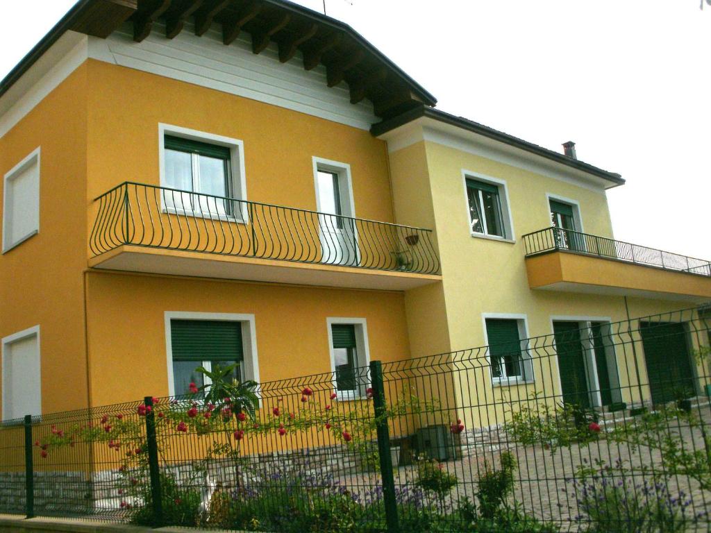 une maison jaune avec un balcon et une clôture dans l'établissement Villa Norma, à Feltre