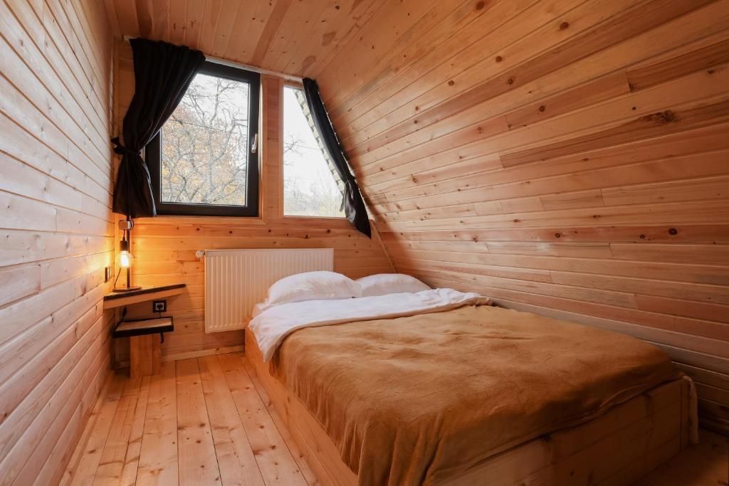 a bedroom with a bed in a wooden room at Cabana Vlad Maramureș in Deseşti