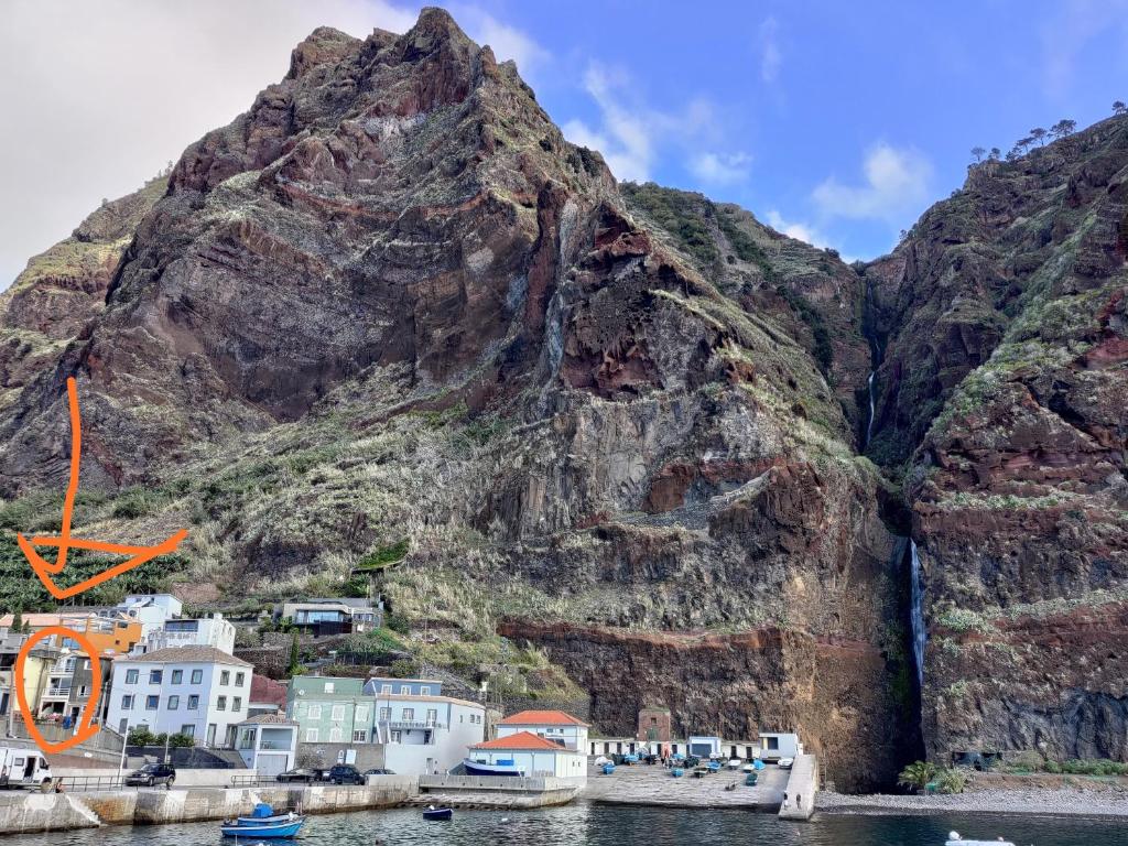 una montagna accanto a un bacino idrico con case e barche di Harbour House a Paul do Mar