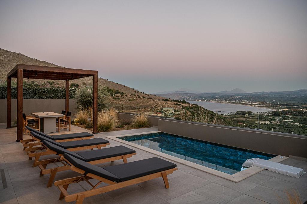 - une piscine avec des chaises longues et une table dans l'établissement ZeusCave, à Georgioúpoli