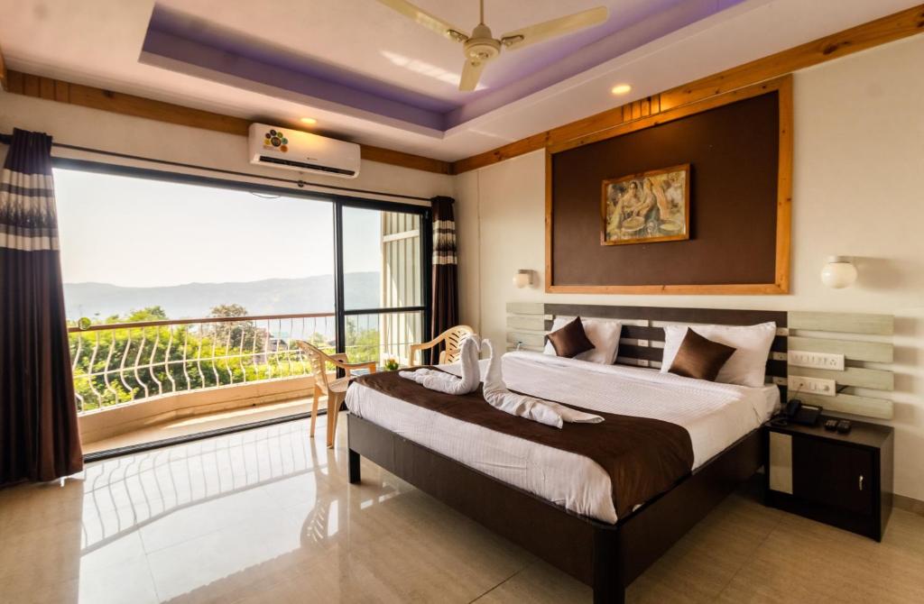 a bedroom with a large bed and a large window at Saga Resort in Mahabaleshwar