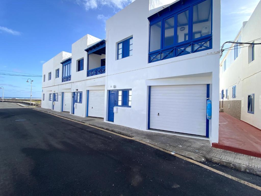 a white building with two garage doors on a street at APARTAMENTO AZUL in Órzola