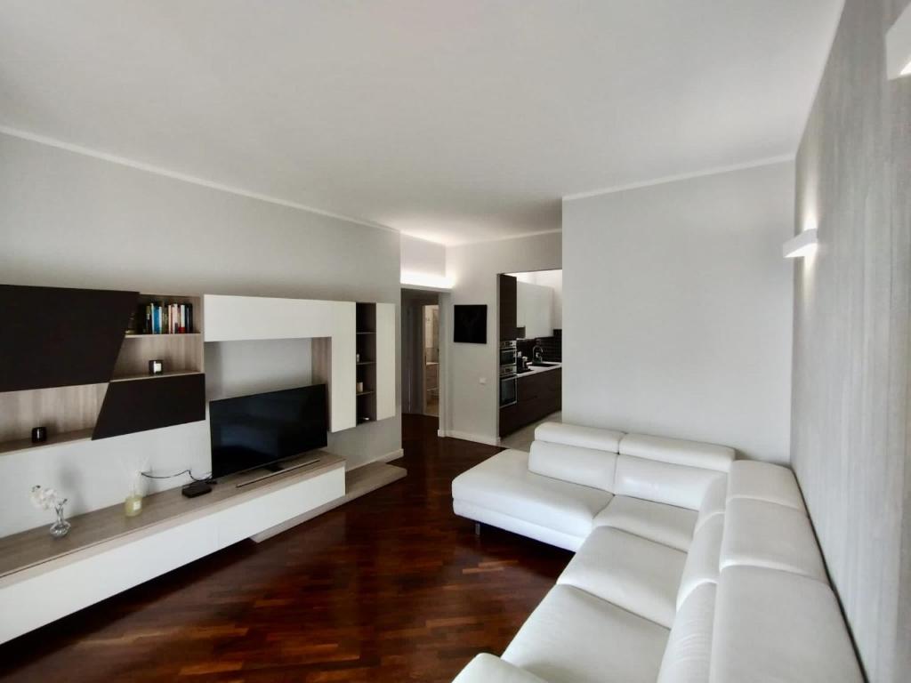 a living room with a white couch and a television at Elisir Home in Genoa