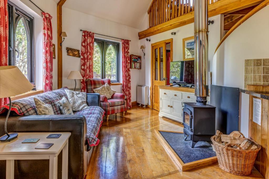 een woonkamer met een bank en een houtkachel bij Kinlochlaich Tree House in Appin