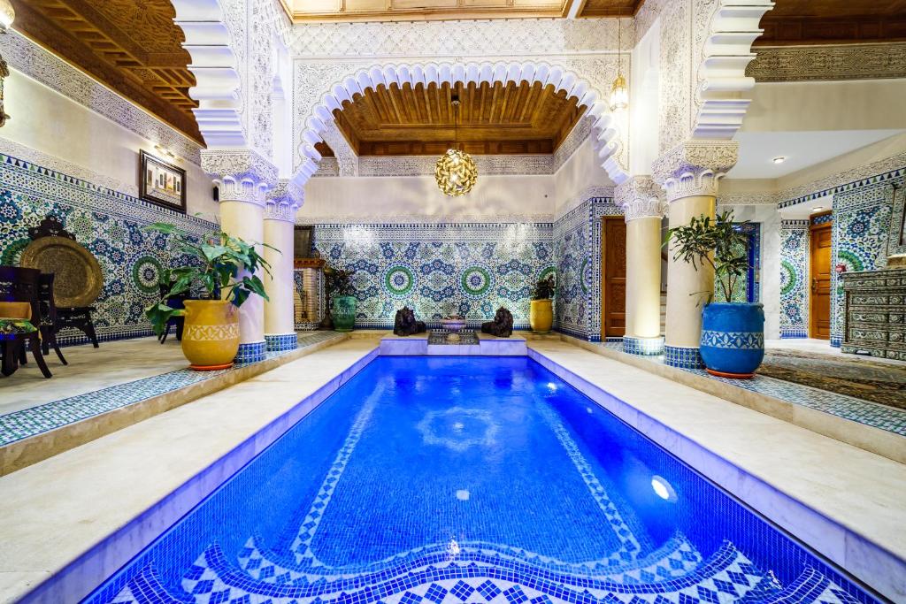 a swimming pool in a large room with a building at Riad Rcif Alif Suite & SPA in Fès