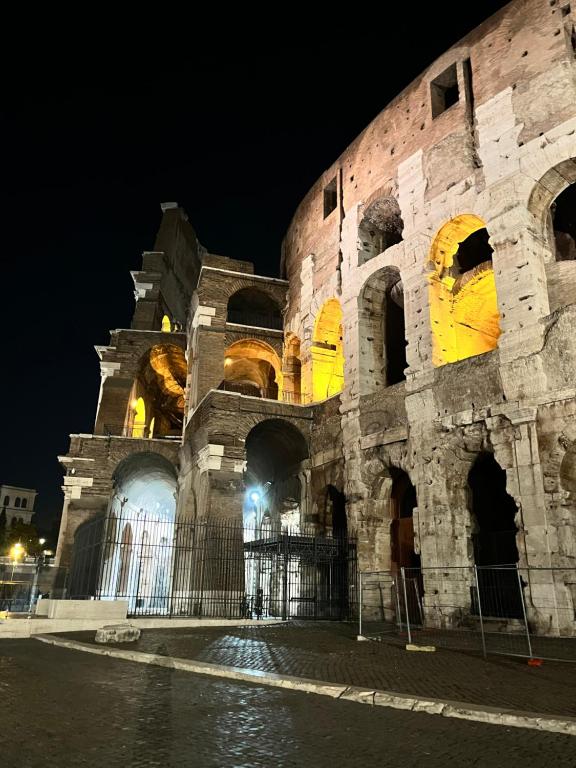 a building at night with yellow lights on it at GladiatoRooms Rome - Colosseo in Rome