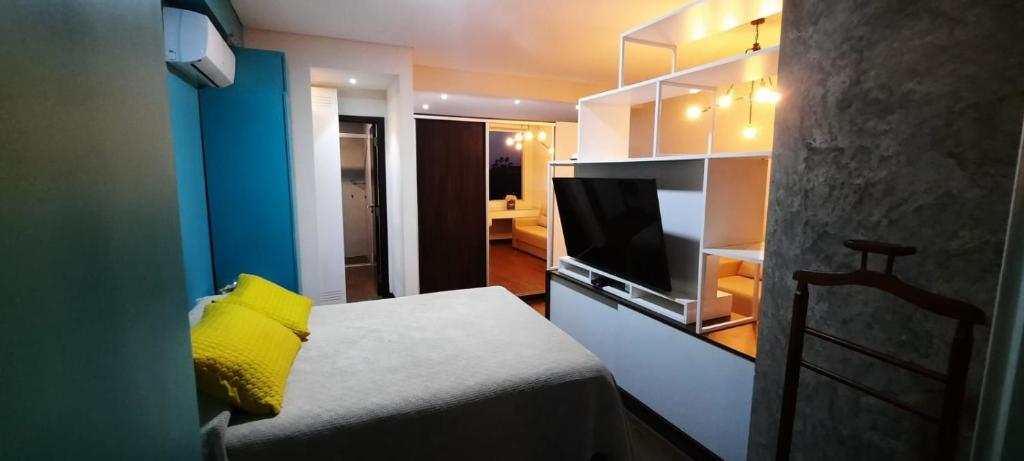 Cette chambre comprend un lit avec un oreiller jaune et une télévision. dans l'établissement Apto en Excelente Zona con Gym Sauna y Jacuzzi, à Santa Cruz de la Sierra