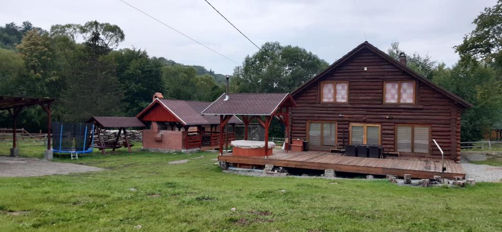 uma casa de madeira com um alpendre e um parque infantil em Magasbükk Drakula Kulcsosház Ivó em Izvoare