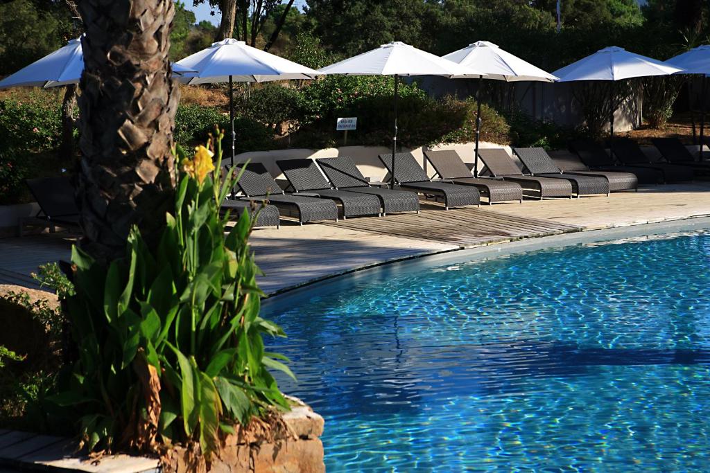 a swimming pool with lounge chairs and umbrellas at Kilina in Porto-Vecchio