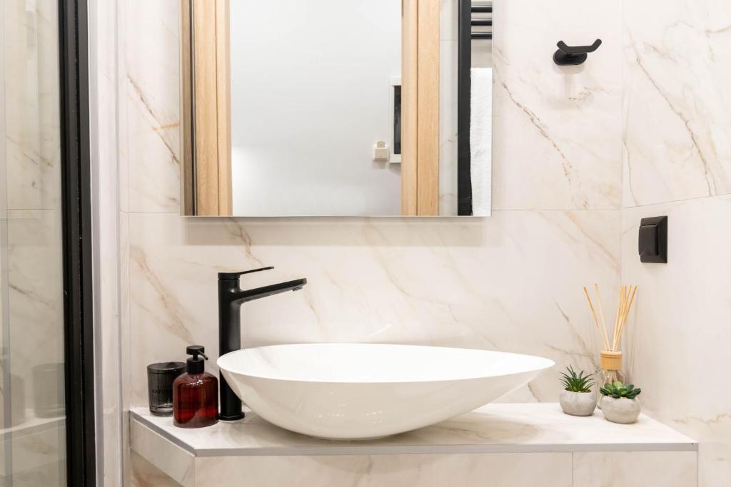 łazienka z białą umywalką i lustrem w obiekcie F & B Collection - City Central 2 Bedroom Suite w Salonikach