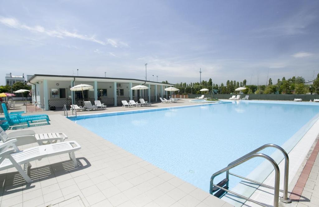 a large swimming pool with chairs and umbrellas at Long Beach Village Residence sul mare spiaggia privata inclusa in Lido Adriano