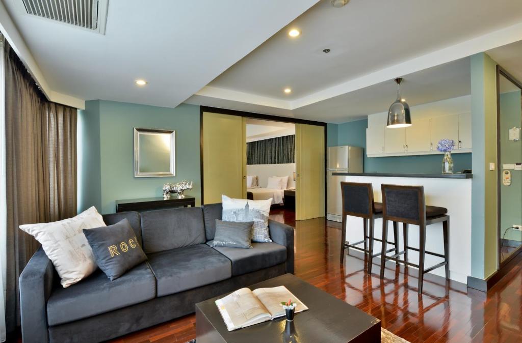 An open-plan apartment living area with a sofa, breakfast bar and a bedroom beyond.