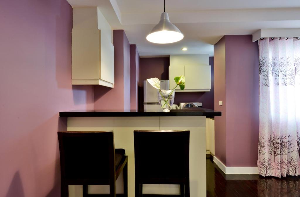 A two-stool breakfast bar beside the apartment kitchen and curtained window.
