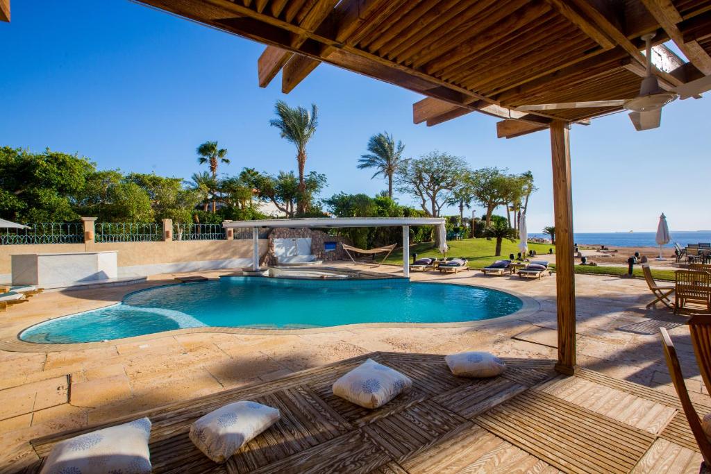 a swimming pool with a table and chairs and the ocean at Ras Katy Sunset Views in Sharm El Sheikh