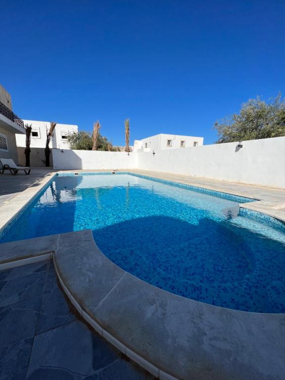 uma piscina com água azul em frente a um edifício em Magnifique villa avec piscine sur l’île de djerba em Houmt Souk