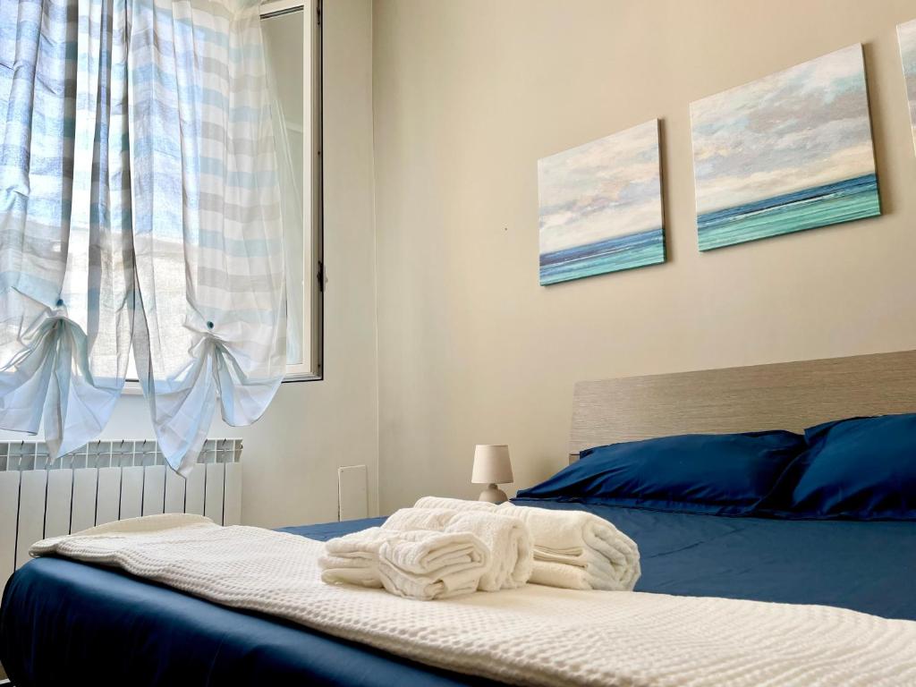 um quarto com uma cama com lençóis azuis e uma janela em CASA GIO'-vista mare,tribunale e castello nel pieno CENTRO di Trani-WIFI em Trani
