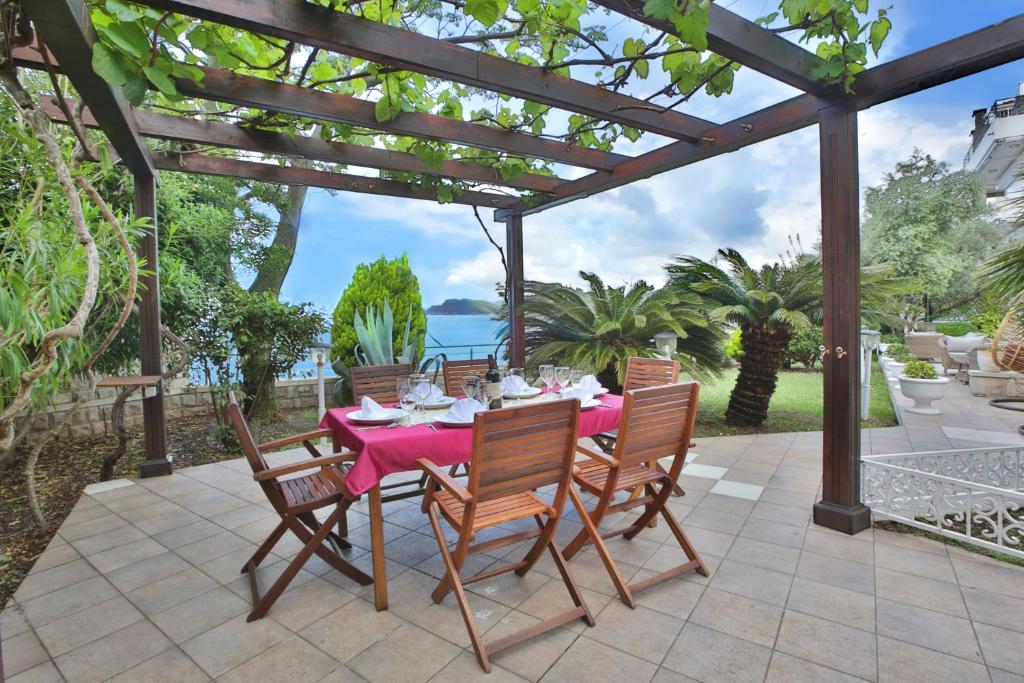 a patio with a table and chairs under a pergola at Royal Holiday Apartments Sveti Stefan DOO PLAVA VILA in Sveti Stefan
