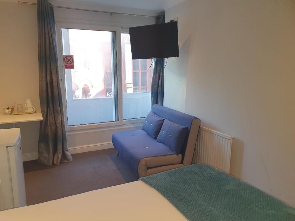 een slaapkamer met een blauwe stoel en een raam bij Blagrave Rooms in Reading