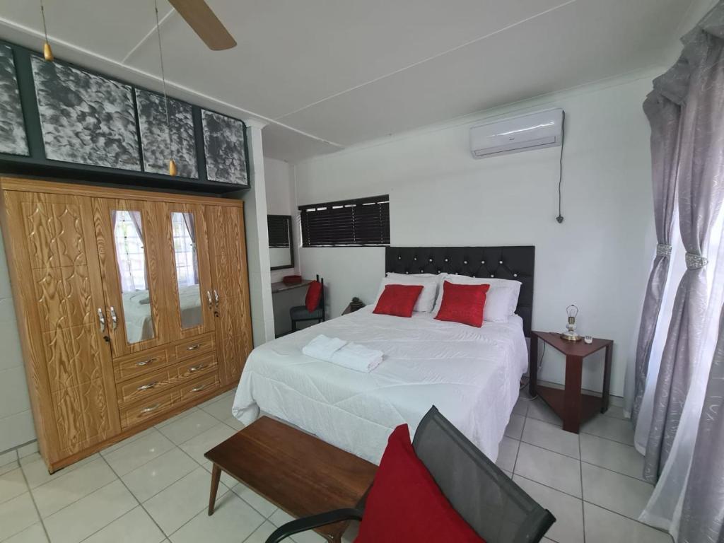 1 dormitorio con cama blanca y almohadas rojas en Chantelle's Overnight Room, en Richards Bay