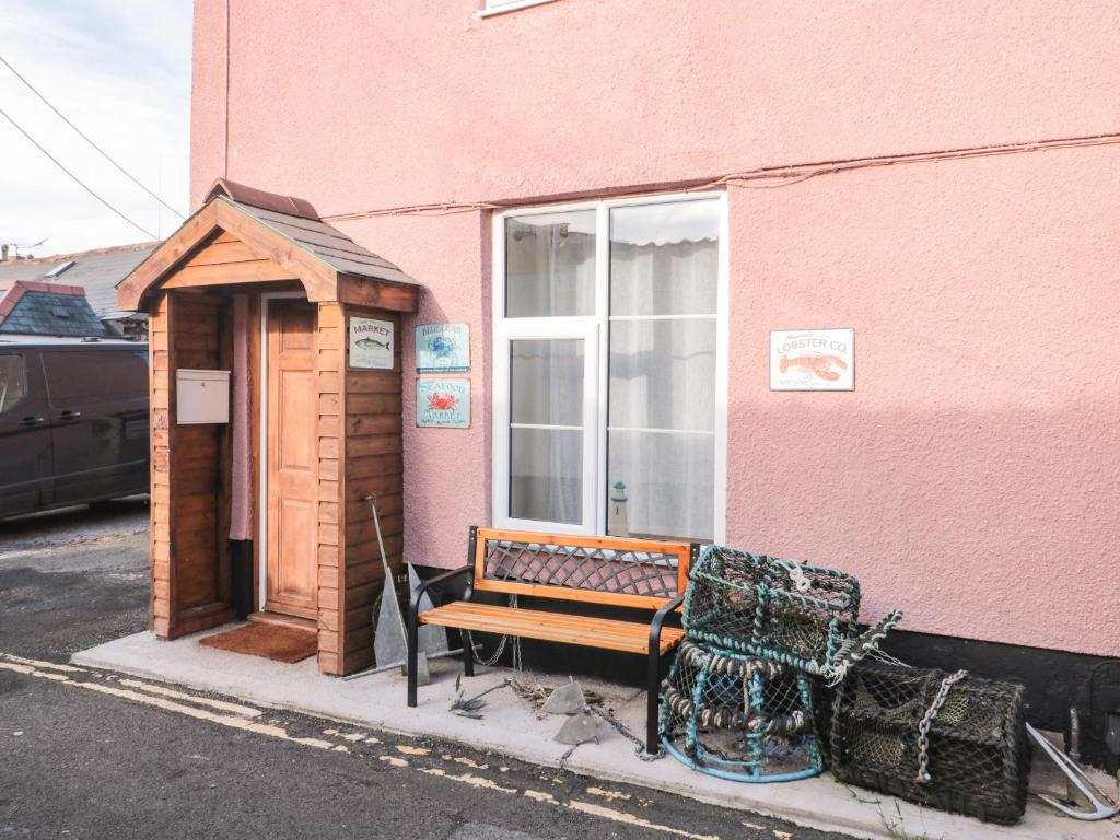 a bench sitting outside of a pink building at The Old Lighthouse Cottage in Watchet