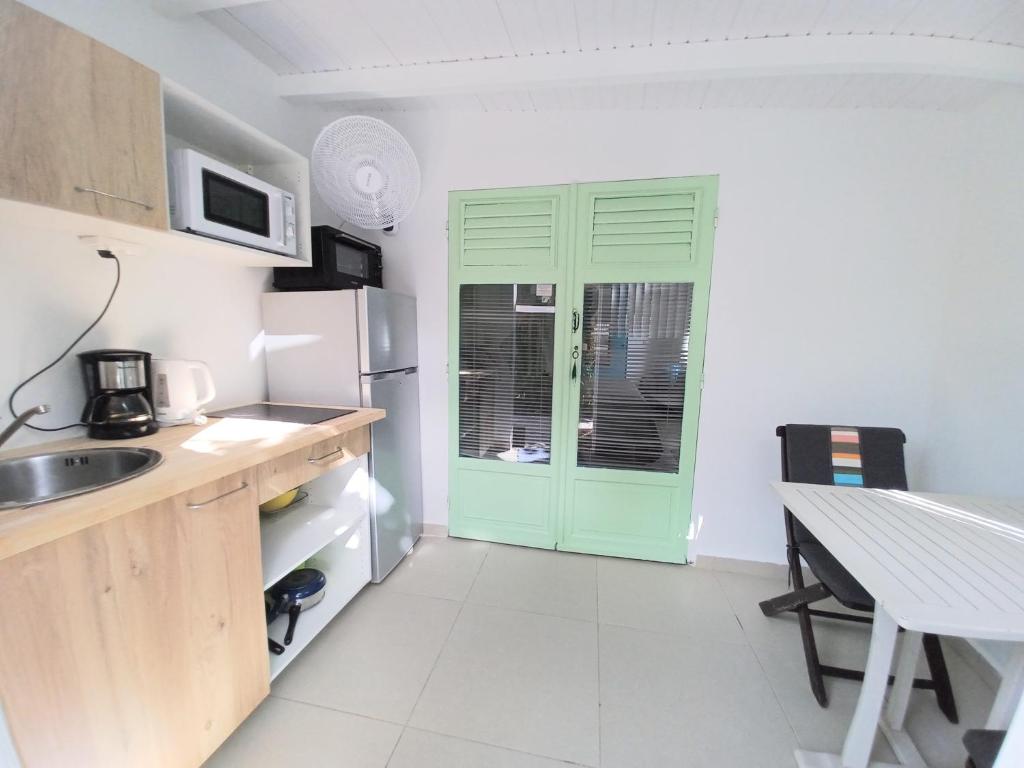 a kitchen with a green door and a table at La Rose du Bresil Marie-Galante in Capesterre