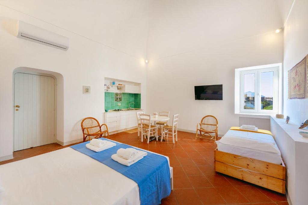sypialnia z 2 łóżkami, stołem i krzesłami w obiekcie TORRETTA CORRICELLA- Punta Serra w mieście Procida