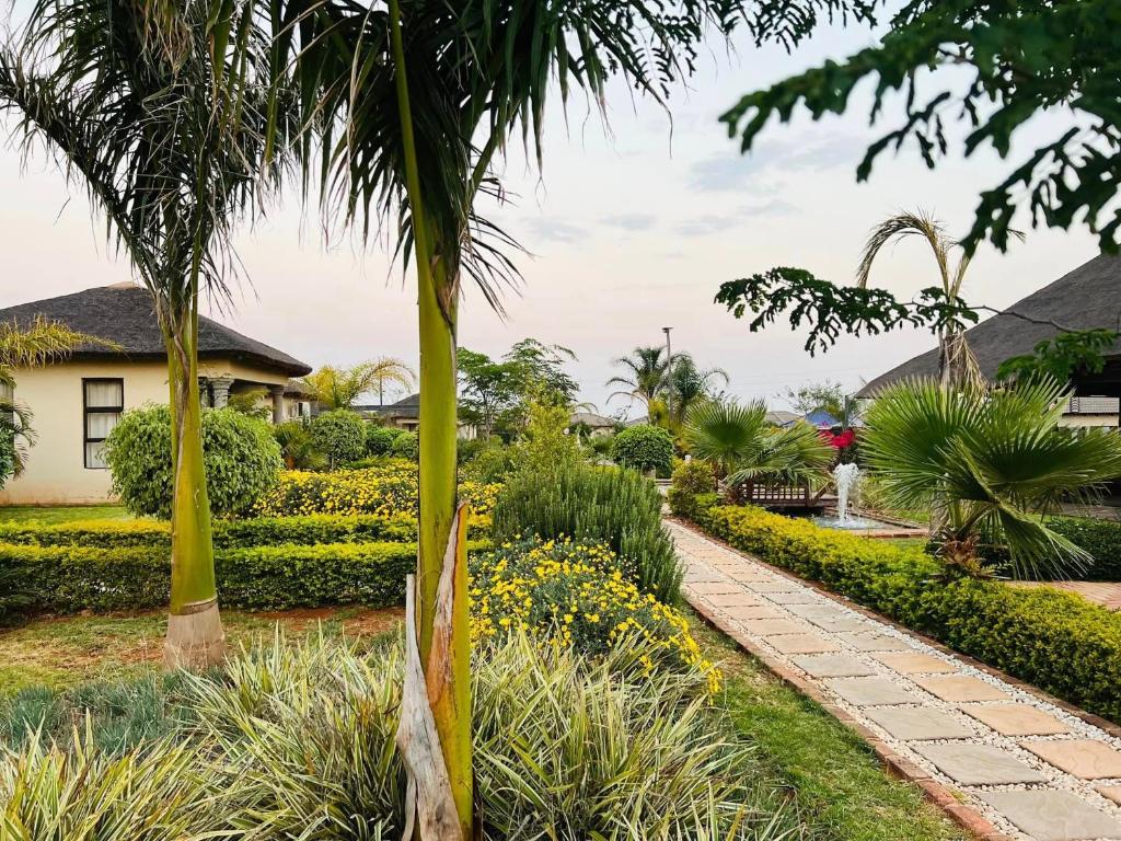 a garden with a palm tree and a walkway at THE BRIDGE BOUTIQUE LODGE in Moletlane