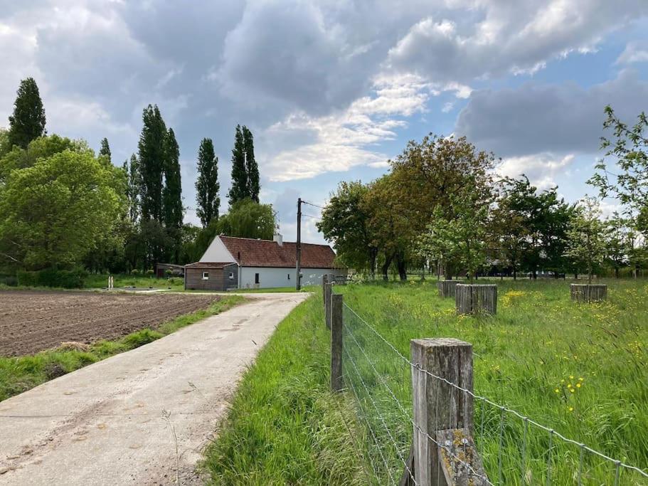 a dirt road next to a field with a fence at Cosy Cott, een verborgen logeerplek in het landelijke Poeke. in Aalter