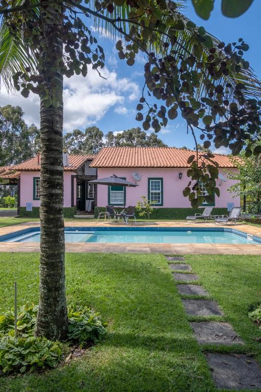 a house with a swimming pool and a palm tree at Sítio Paraíso Beach Tennis in Vassouras