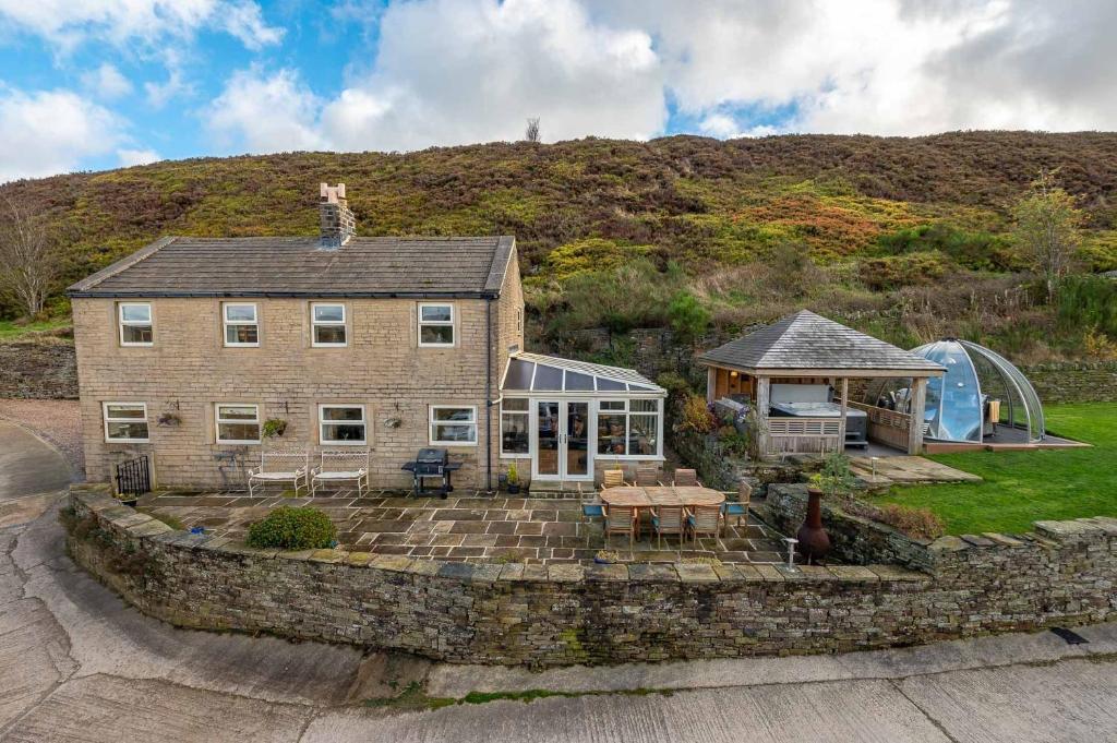 uma grande casa de tijolos com uma mesa em frente em Bilberry Bank Cottage em Holmfirth