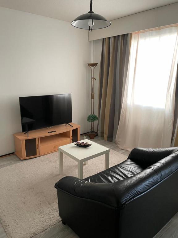 a living room with a couch and a tv and a table at Lovely apartment within walking distance -centre in Pori