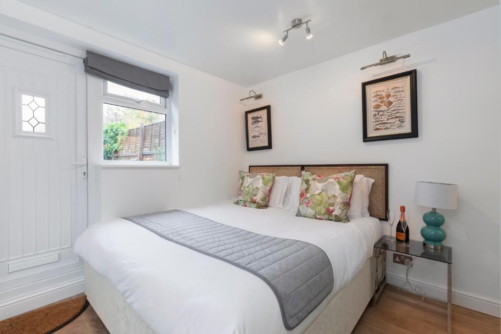 a white bedroom with a bed and a window at Modern Self Contained Studio Home in Cheltenham