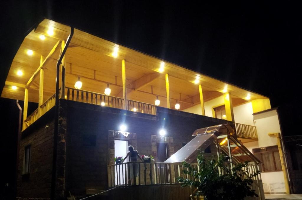un hombre de pie en el balcón de una casa por la noche en NUR TOON, en Areni