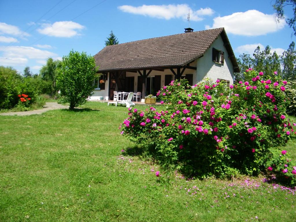 une maison avec des fleurs roses devant une cour dans l'établissement Chambre d'hôtes à la campagne "Le coudry", à Serley