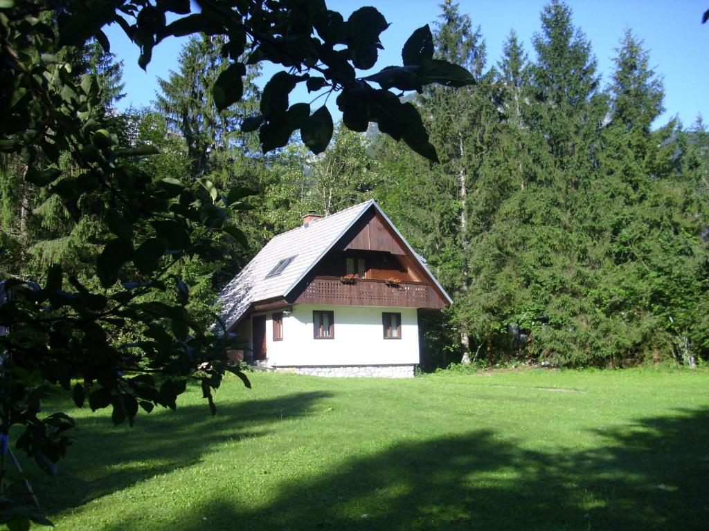 una pequeña casa blanca en un campo con árboles en Apartment Lake Bohinj no. 5, en Bohinj