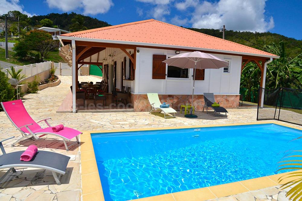 a house with a swimming pool in front of a house at Villa Sohalia climatisée, piscine et jardin à 5mn de la plage in Le Diamant