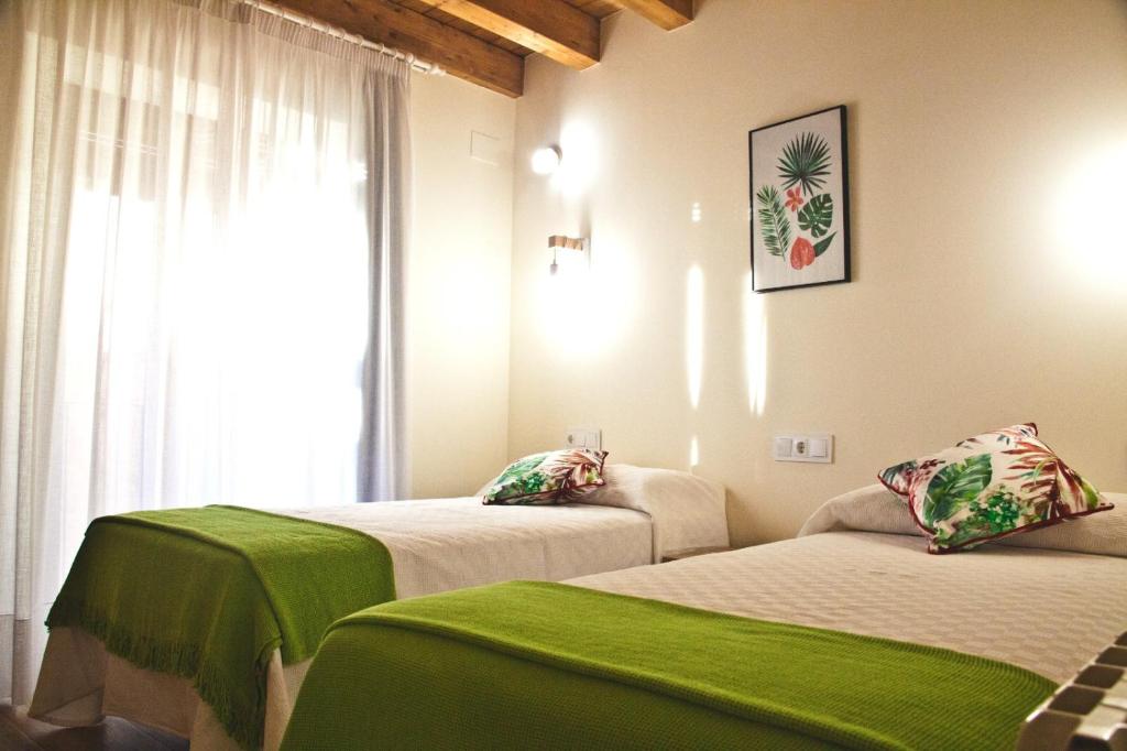 a room with two beds with green sheets and a window at CASA RURAL LA MANFORTA in Gata