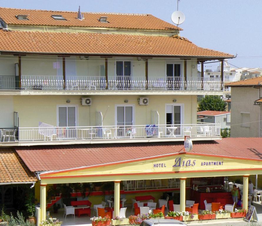 a building with a balcony and tables and chairs at Hotel Dias Apartment in Makrygialos