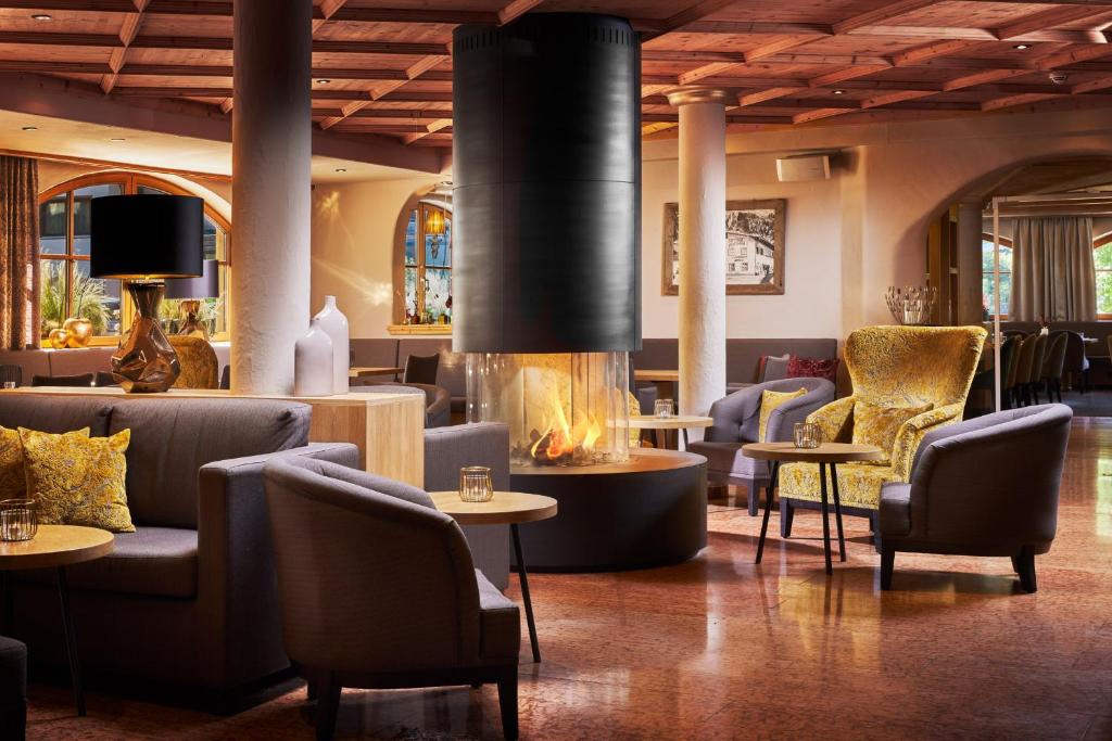 eine Lobby mit Sofas und Stühlen sowie einem Kamin in der Unterkunft Alpinresort Stubaierhof ****s in Fulpmes