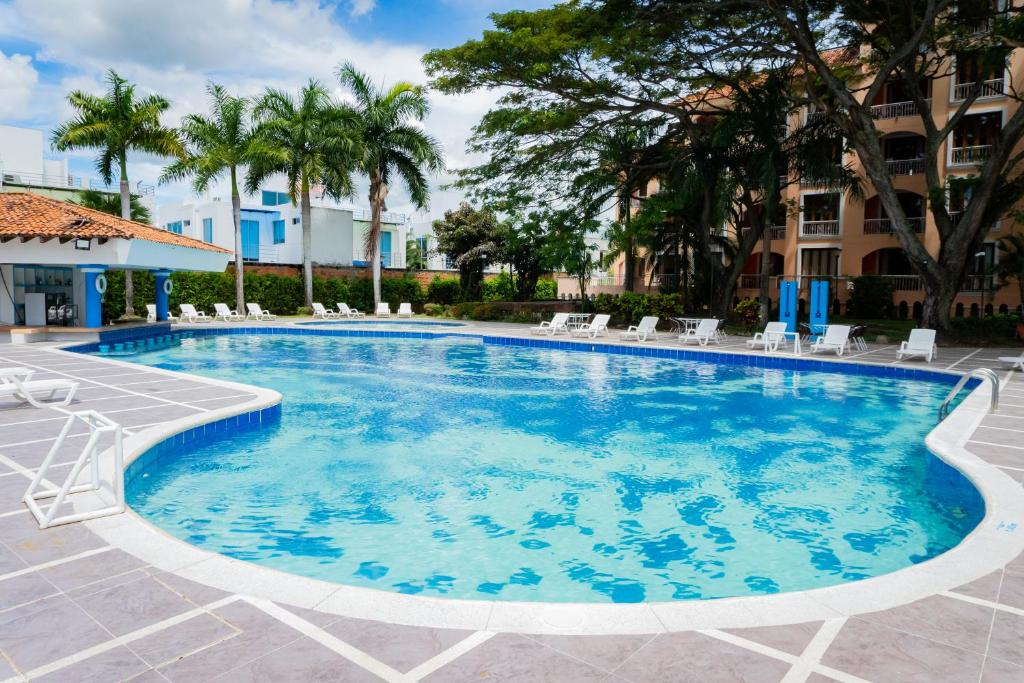 een zwembad in een resort met stoelen en bomen bij Hotel Peñon Suites in Girardot